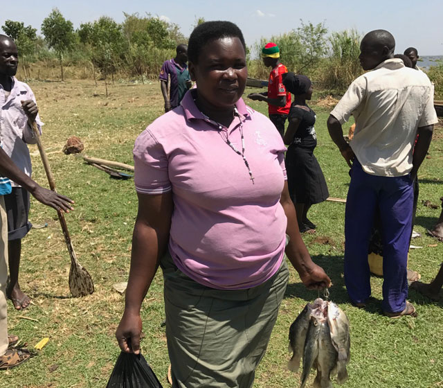 Betty buying fish at Lake Kyoga in Uganda. Betty is a member of the Fr Omoding Primary School village savings group, set up by Drop in the Bucket