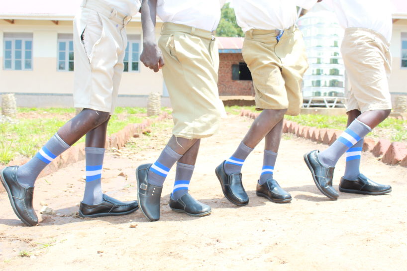 Four boys in Uganda show of their new shoes