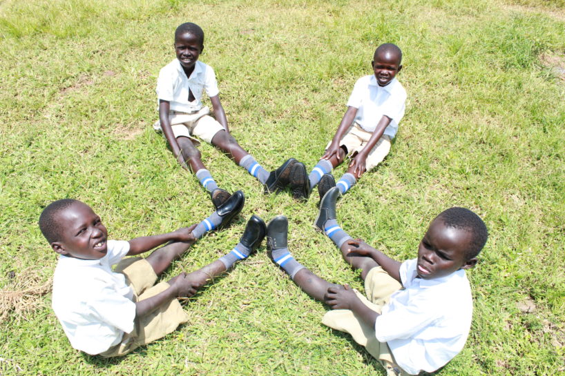 Four young students line up their shoes together in a school in Uganda 