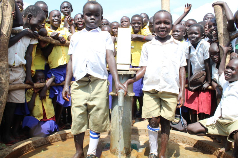 School children in Uganda gather round two boys who share a pair of shoes