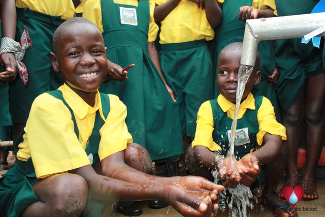 Two Happy Students In Uganda Smiling At Clean Water Well