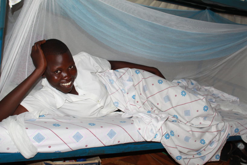 A young female student lays down in her dorm bunk in Uganda