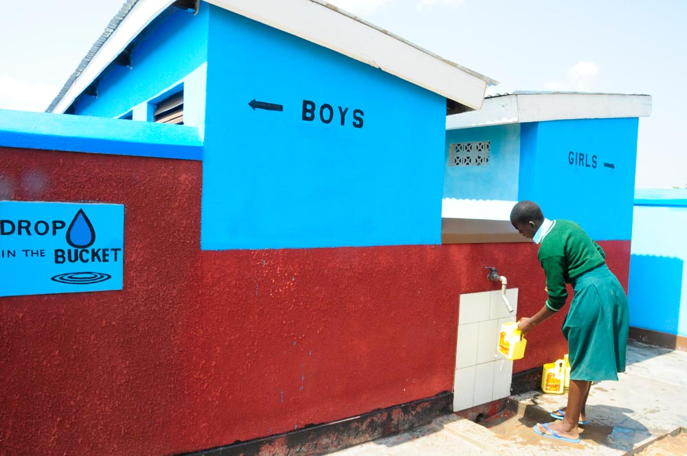 A Ugandan girl collects water to flush Drop in the Bucket’s bio-digestion toilet at an East African school, an eco-friendly sanitation system that treats waste instead of storing it.
