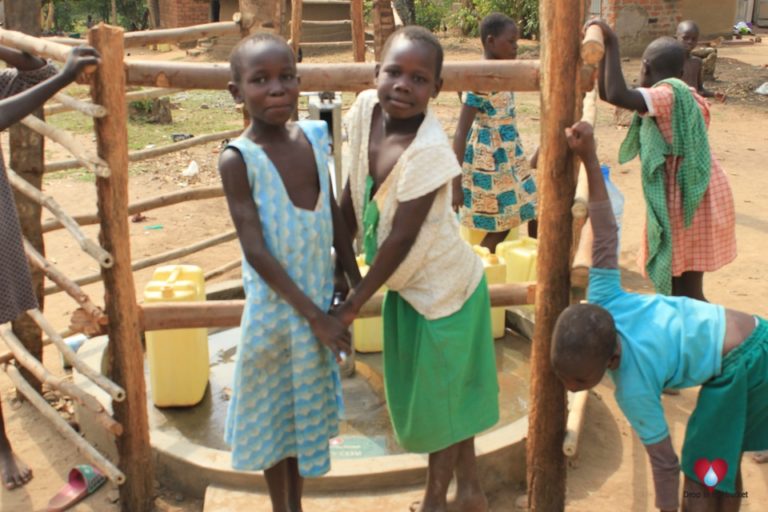 Two girls at a borehole well drilled by Drop in the Bucket for the Goan Quarters community in Gulu, Uganda.