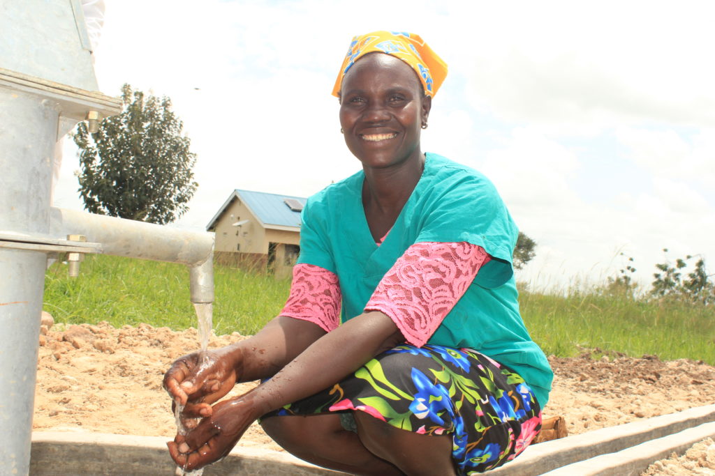 A staff member at Wii Anaka Health Center II in Nwoya, Uganda, collects clean water from a well drilled by Drop in the Bucket in 2021.