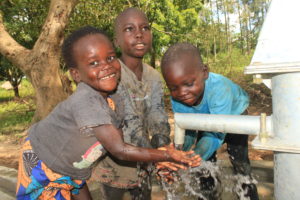 Three children getting clean water from the well drilled by US based water charity Drop in the Bucket at the Ogwari Community school in Omoro, Uganda