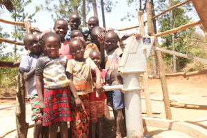 Children stand by a water well at Apur Ki Opoko village in Uganda drilled by Drop in the Bucket