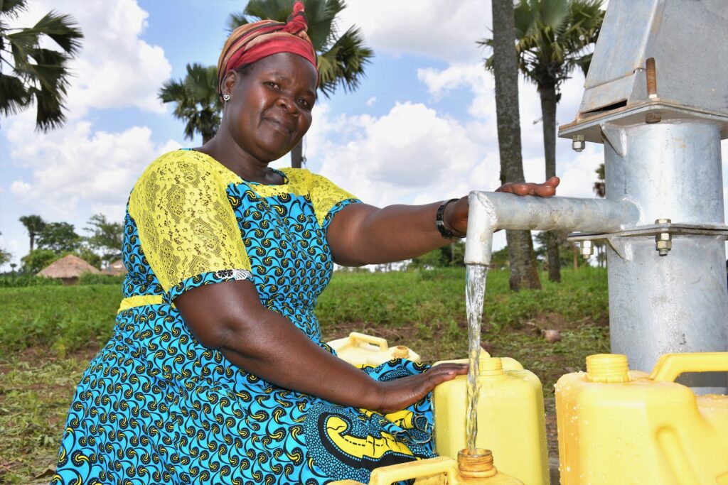 A woman collects clean water from a well in Layik West village, Kitgum, Uganda, drilled by Drop in the Bucket.