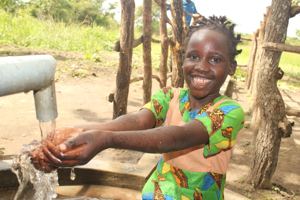 A girl drinks clean water from the new well at Laminogwiri village in Omoro, Uganda, drilled by Drop in the Bucket in 2022
