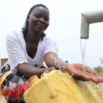 A woman cleans her jerrycan in the recently drilled water well at the Angole Health Center in Pader Uganda.
