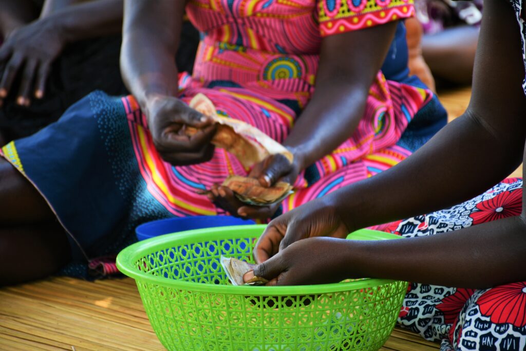 A woman receives money at a VSLA meeting in Uganda set up by the non-profit Drop in the Bucket