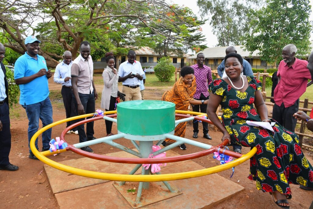 Local government officials try out the roundabout pump at Kasubi Central Primary School.