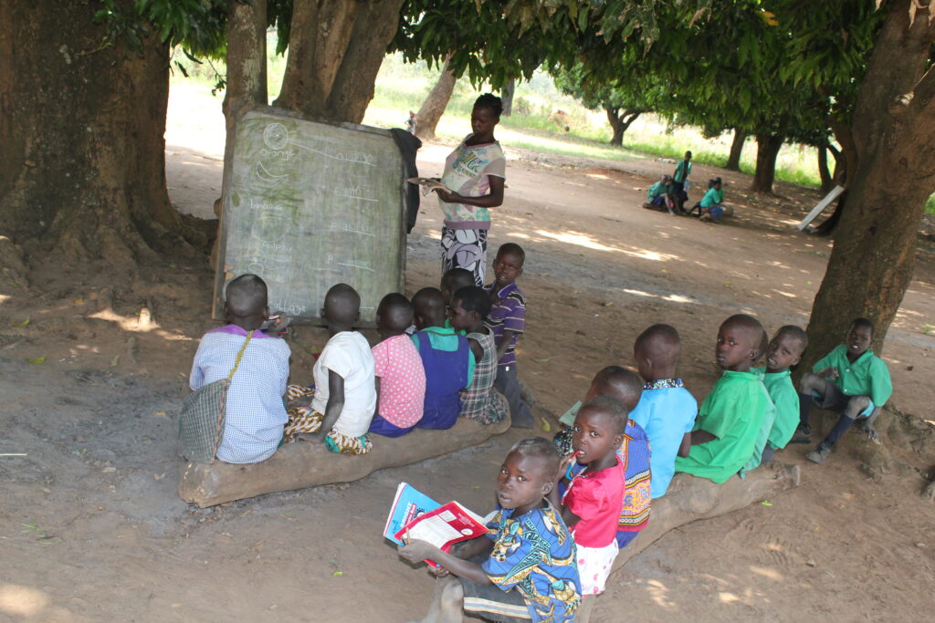 A class of schoolchildren studying under a tree at Paitino Primary School in Pader, Uganda, with clean water provided by a well drilled by Drop in the Bucket.
