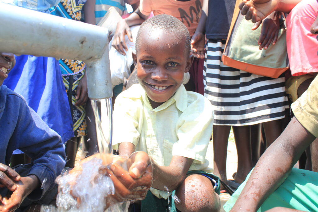 A young boy collects clean water from a borehole in Atwomo village, Nwoya, Uganda, drilled by Drop in the Bucket.
