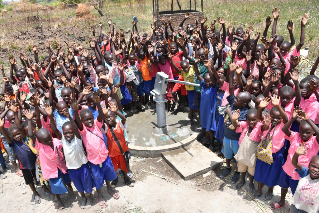 Students from the Ongai Primary School in Uganda stand around the well drilled by Drop in the Bucket