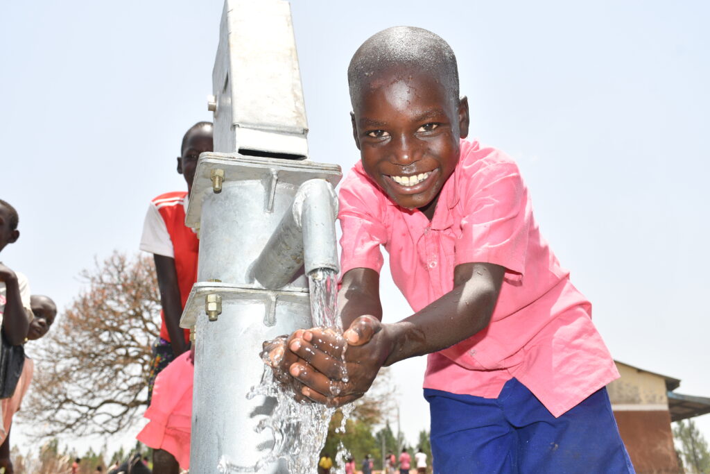 A child gets clean water from the new well at the Ongai Primary School in Nwoya, Uganda drilled by Drop in the Bucket