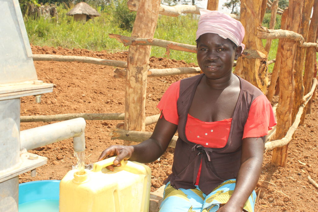 Woman collecting clean water from a well in Omoro district, Uganda, provided by Drop in the Bucket.