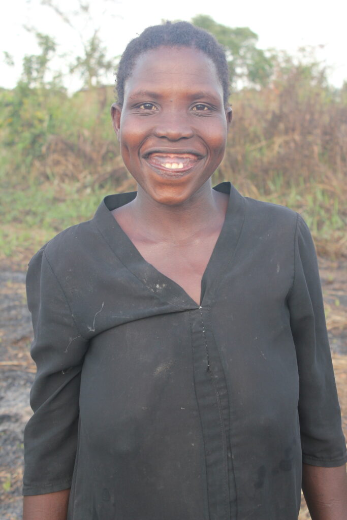 Nancy Atim smiles proudly as she stands near the new well in the Akecha B village in Omoro, Uganda.