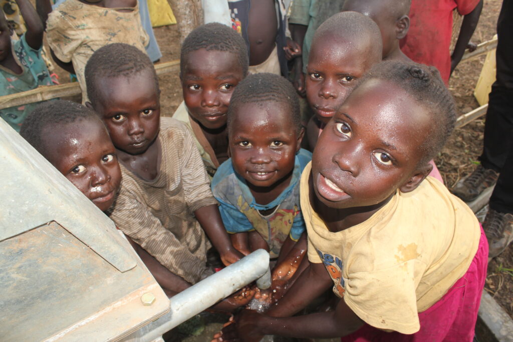 Children getting clean water from the new well at Akecha B village in Omoro, Uganda drilled by Drop in the Bucket