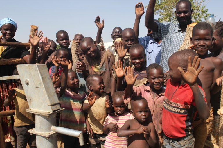 Children from Ngom Rom village stand by the new well drilled by Drop in the Bucket