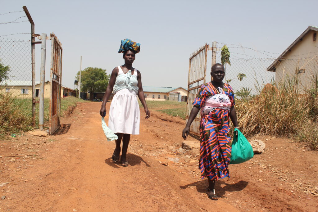 Two mothers exit the health centers’ gate after receiving treatment. cat the Alero Health Center III, Nwoya, Uganda
