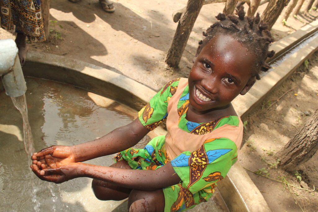 A girl collecting clean water from the new well in Laminogwiri village, Omoro, Uganda, drilled by Drop in the Bucket.