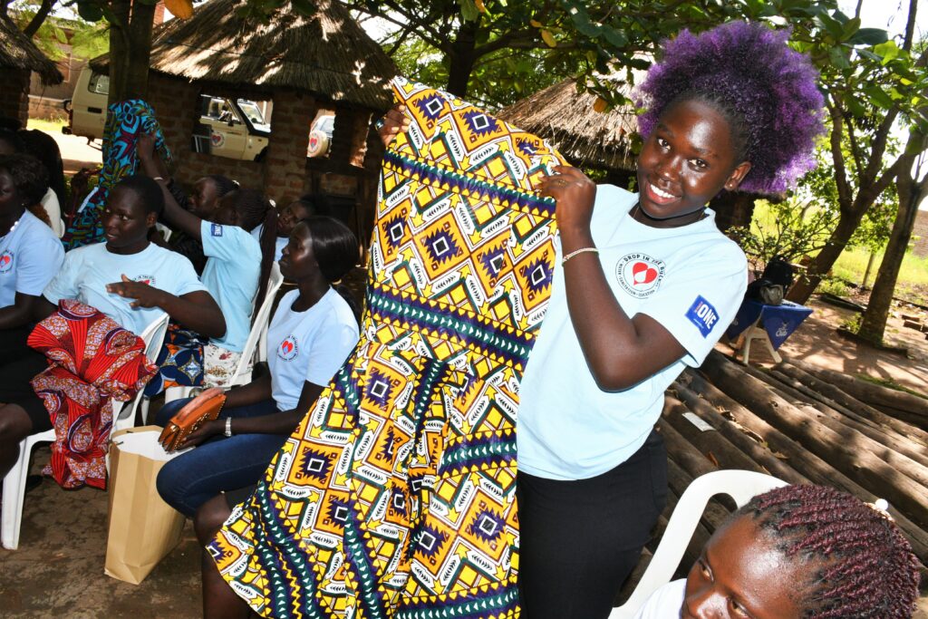 A graduating student from Drop in the Bucket's education program in Nimule, South Sudan shows off her new dress. 