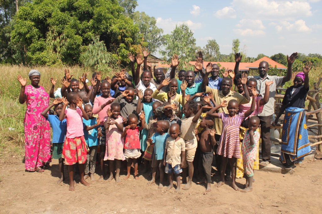 Villagers in Kati Kati, Gulu, Uganda celebrate beside the new water well drilled by Drop in the Bucket.