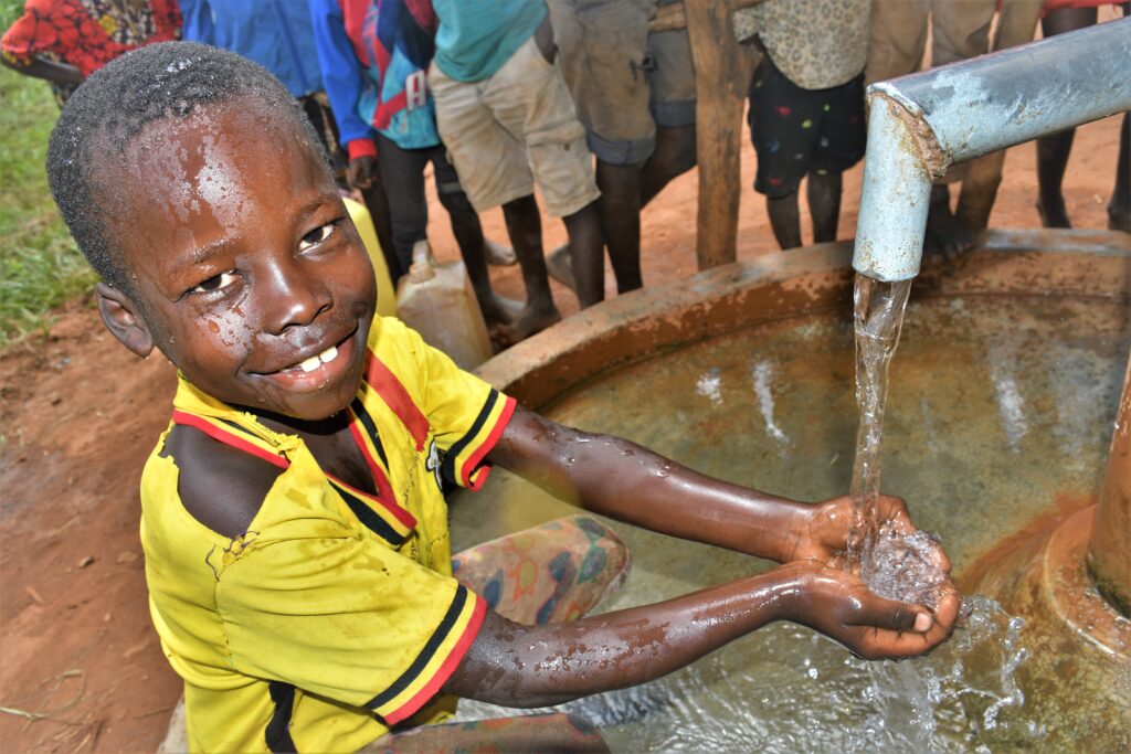 Boy gets clean water from the well at Twon Okun drilled by Los Angeles water charity Drop in the Bucket