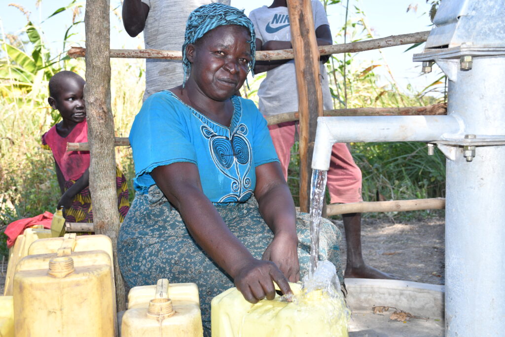 A woman collects clean water from a well in Lumec village, Omoro, Uganda, made possible by Drop in the Bucket’s water charity efforts.