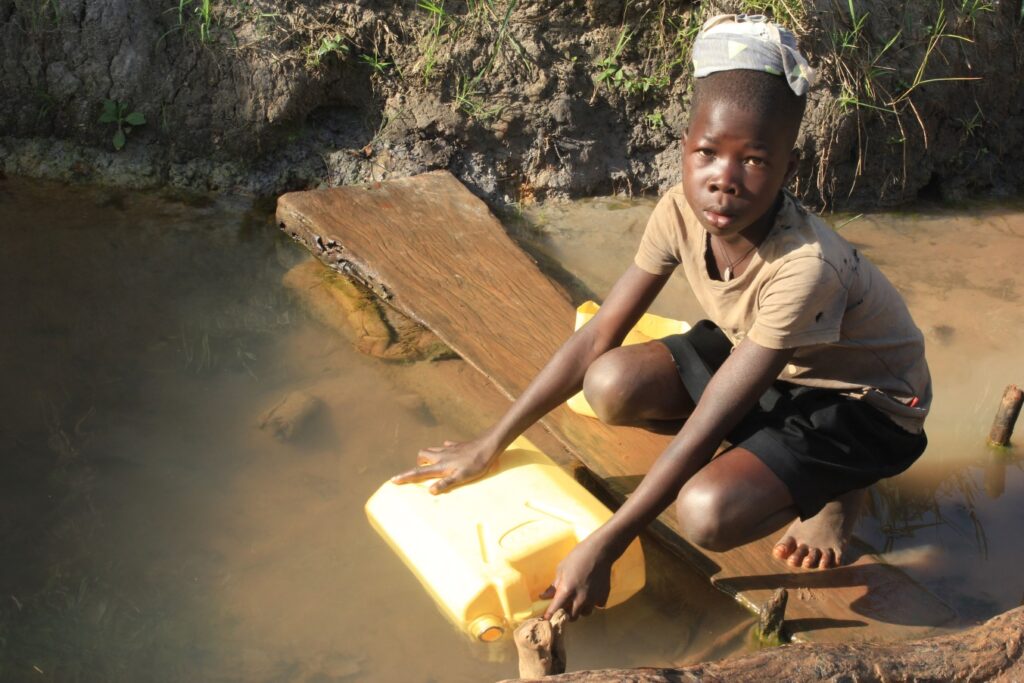 A Young boy named Anena Milgrate fetches water from a waterhole in Twon Okun Uganda