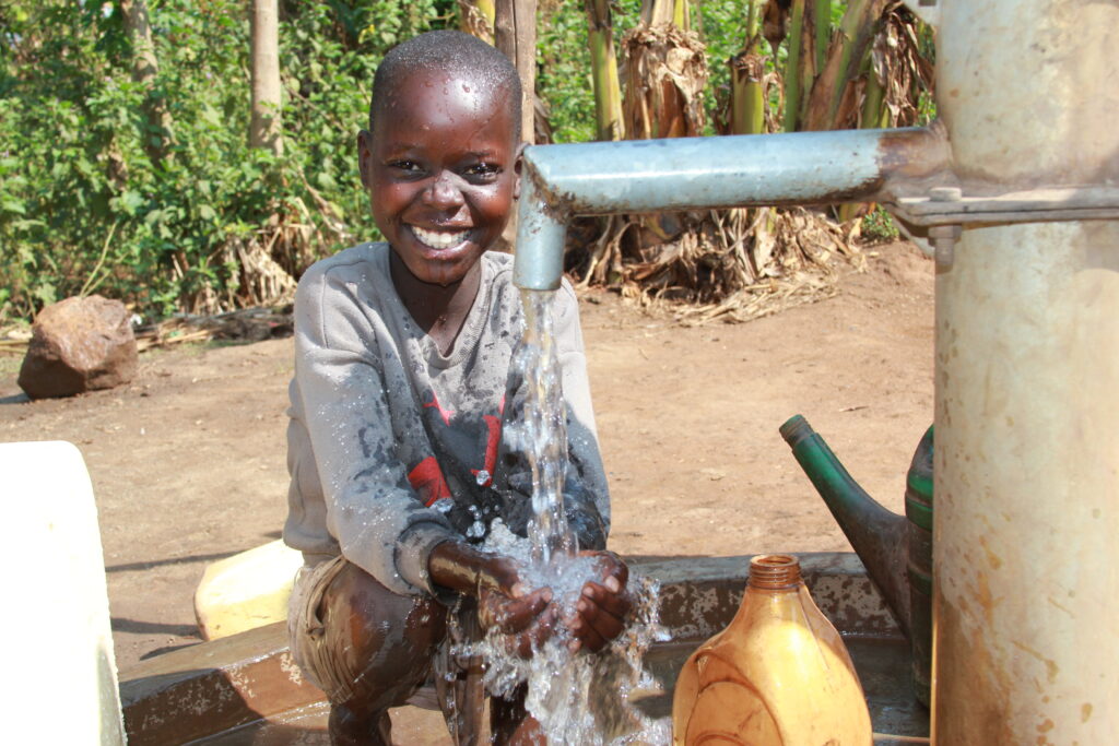 A young boy getting clean water from the new water well at Aleng C village in Uganda drilled by Drop in the Bucket