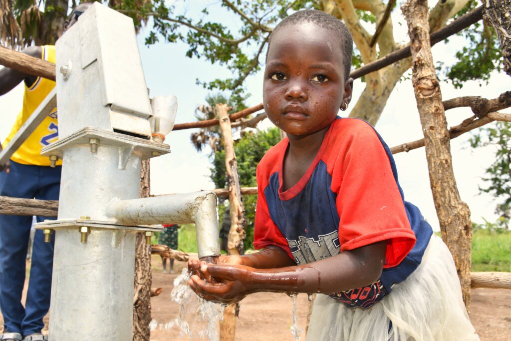 Young Girl Draws Safe Water at Abegu Borehole - Drop In the Bucket School-aged girl fills a yellow jerrycan with clean water at the new Drop in the Bucket well in Abegu Village, Gulu District.