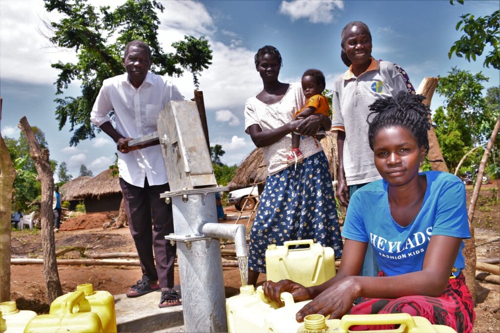 Community Members from Laliya Dwol in the Gulu District of Uganda stand by the new well drilled by Drop in the Bucket