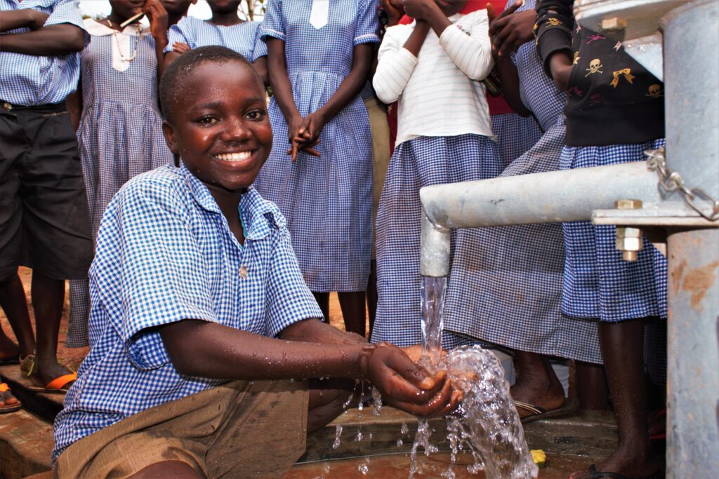 A male student gets clean water from a well at the Buyubu primary school in Iganga, Uganda drilled by Drop in the Bucket