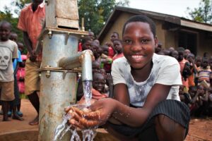 A girl students from the Buliganwa Primary School in Uganda gets clean water from the new well drilled by Drop in the Bucket