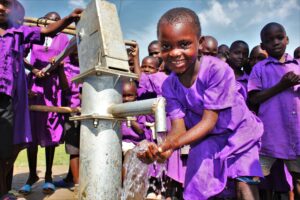 A girl gets clean water from the new well at the Bukwaya Primary School in Imanyiro, Uganda