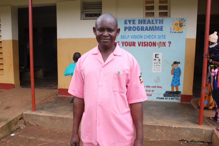 Kamoyi Wilson nurse at the Naibiri Health Center II in Uganda - Drop In the Bucket Kamoyi Wilson stands in front of the Naibiri Health Center II where he works as a nurse.