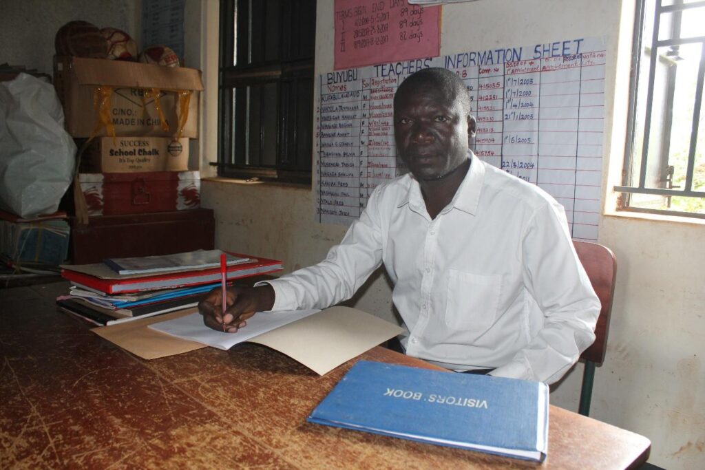 David Kufabulala headteacher Buyubu school Iganga, Uganda - Drop In the Bucket The headteacher at the Buyubu Primary School in Iganga, Uganda sits at the desk in his office