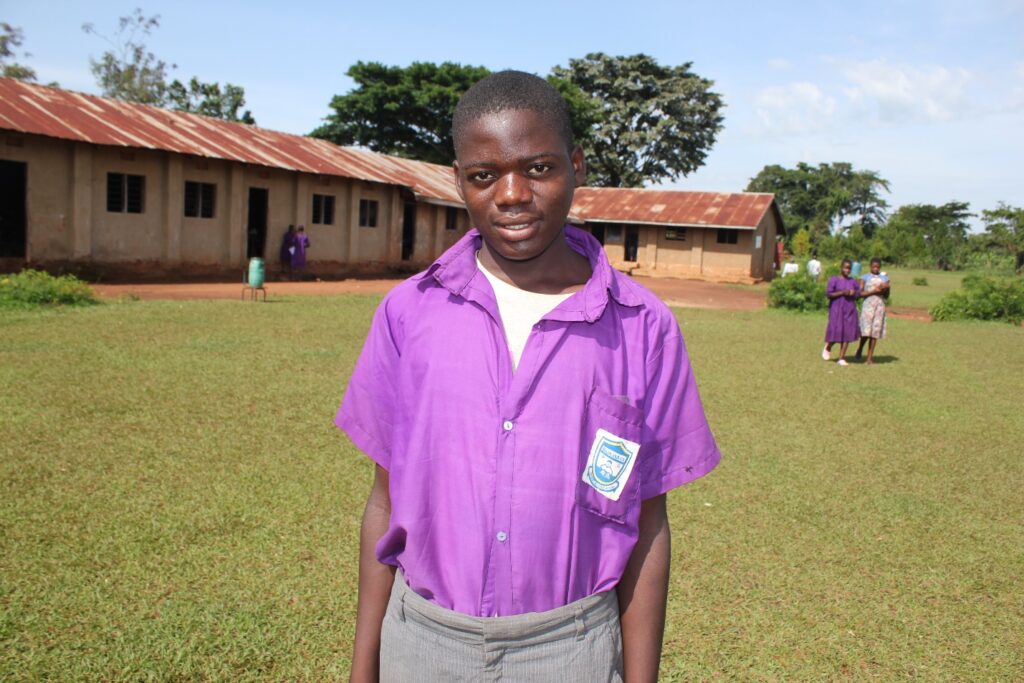 Bukwaya Primary School Imanyiro Uganda - Drop In the Bucket Abed Bafumba student at the Bukwaya Primary School in Imanyiro, Uganda stands in front of one of the classrooms