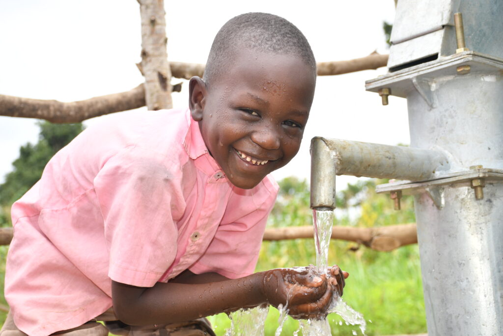 A young Ugandan boy gets clean water water from a borehole well drilled in Paminano-A Cell village.
