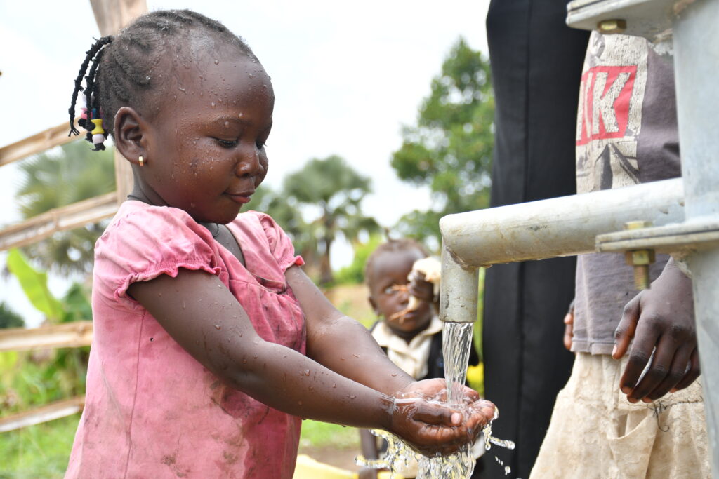 A Ugandan girl gets safe water from a borehole well drilled in Paminano-A Cell village.