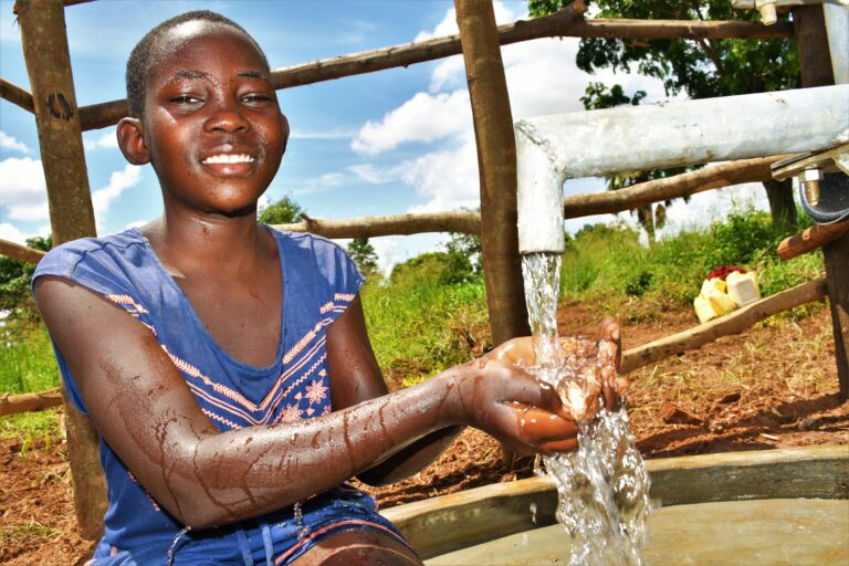 A girl gets clean water from the new well drilled by Uganda water charity Drop in the Bucket