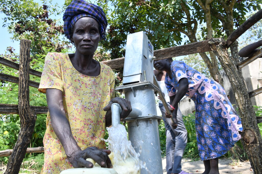 Village woman gets clean water from the new well at the Covenant Nursery and primary school in Okura, Uganda drilled by Africa water charity Drop in the Bucket
