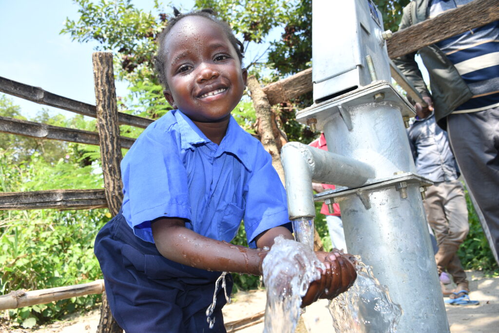 A boy gets clean water from the new well at the Covenant Nursery and primary school in Okura, Uganda drilled by Africa water charity Drop in the Bucket