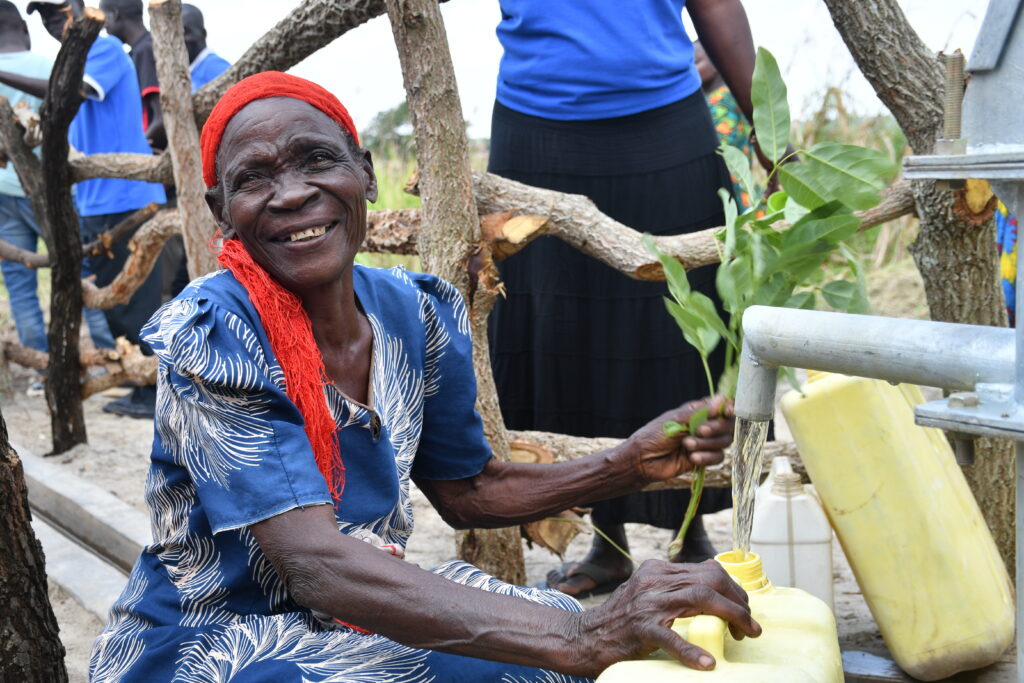 Older woman getting clean water from the new well in Lakwatomer village in northern Uganda