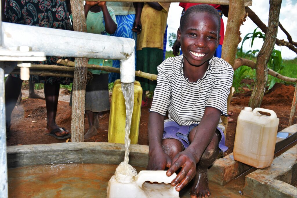 A girl from the Lamin Lawino Ogwari village in Uganda gets clean water from the well drilled by Los Angeles water charity Drop in the Bucket