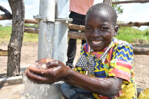 Lakwatomer borehole-Uganda-06 - Drop In the Bucket Young boy getting clean water from the new borehole in Lakwatomer village in northern Uganda