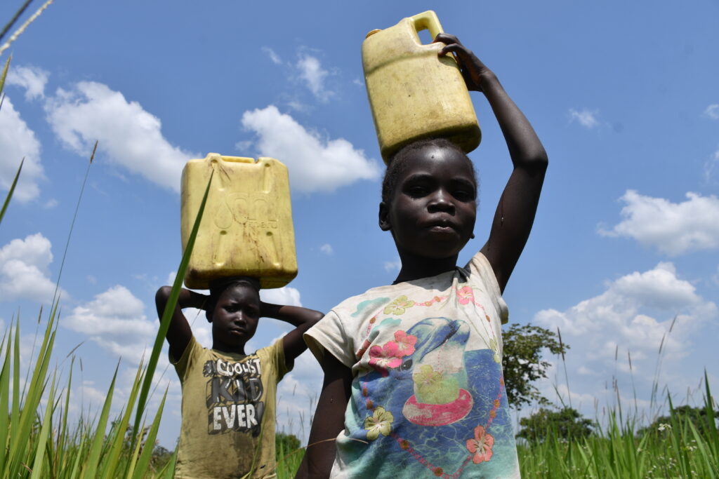 Two girls carrying dirty jerry cans full of unsafe water near Lakwatomer village in northern 