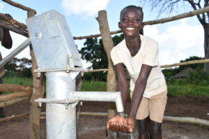A boy getting water from the new well in Lwokagulu village in Iganga, Uganda